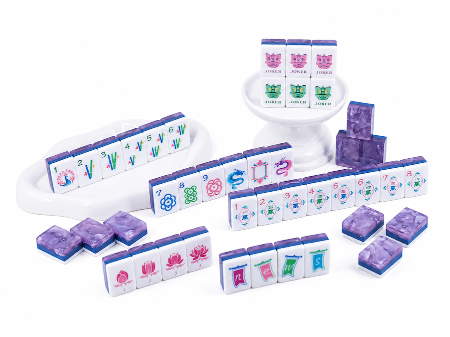 Mahjong tiles on a white tray with stacked pieces and scattered purple-backed tiles