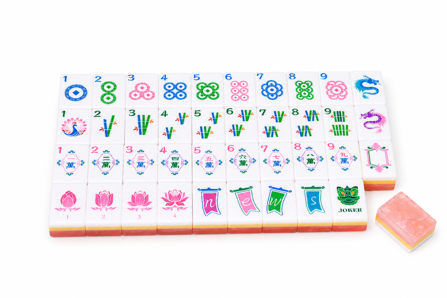 Mahjong tile set with arranged tile faces and two loose peach-pink tiles