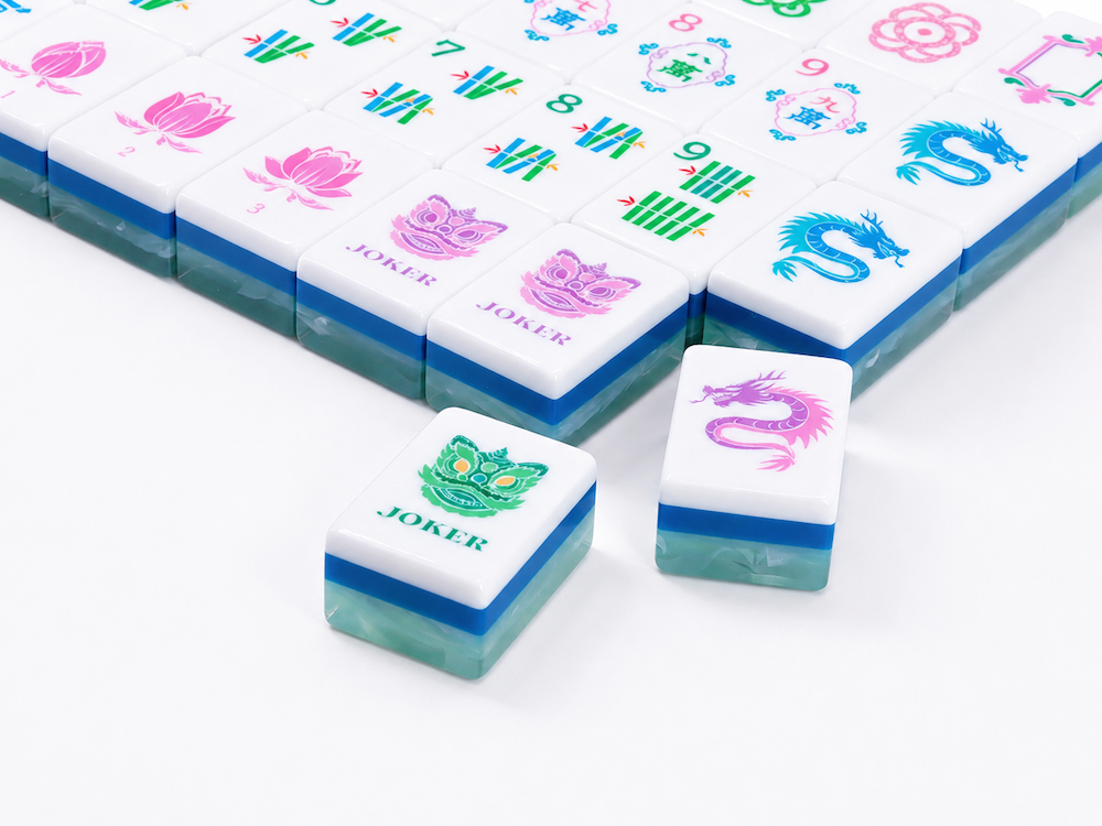 Close-up of white Mahjong tiles with colorful flower, wind, and dragon symbols