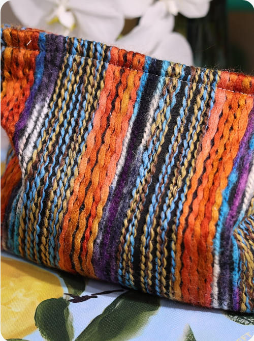 Multicolor woven stripe pouch with vertical knit stripes in orange, purple, and blue