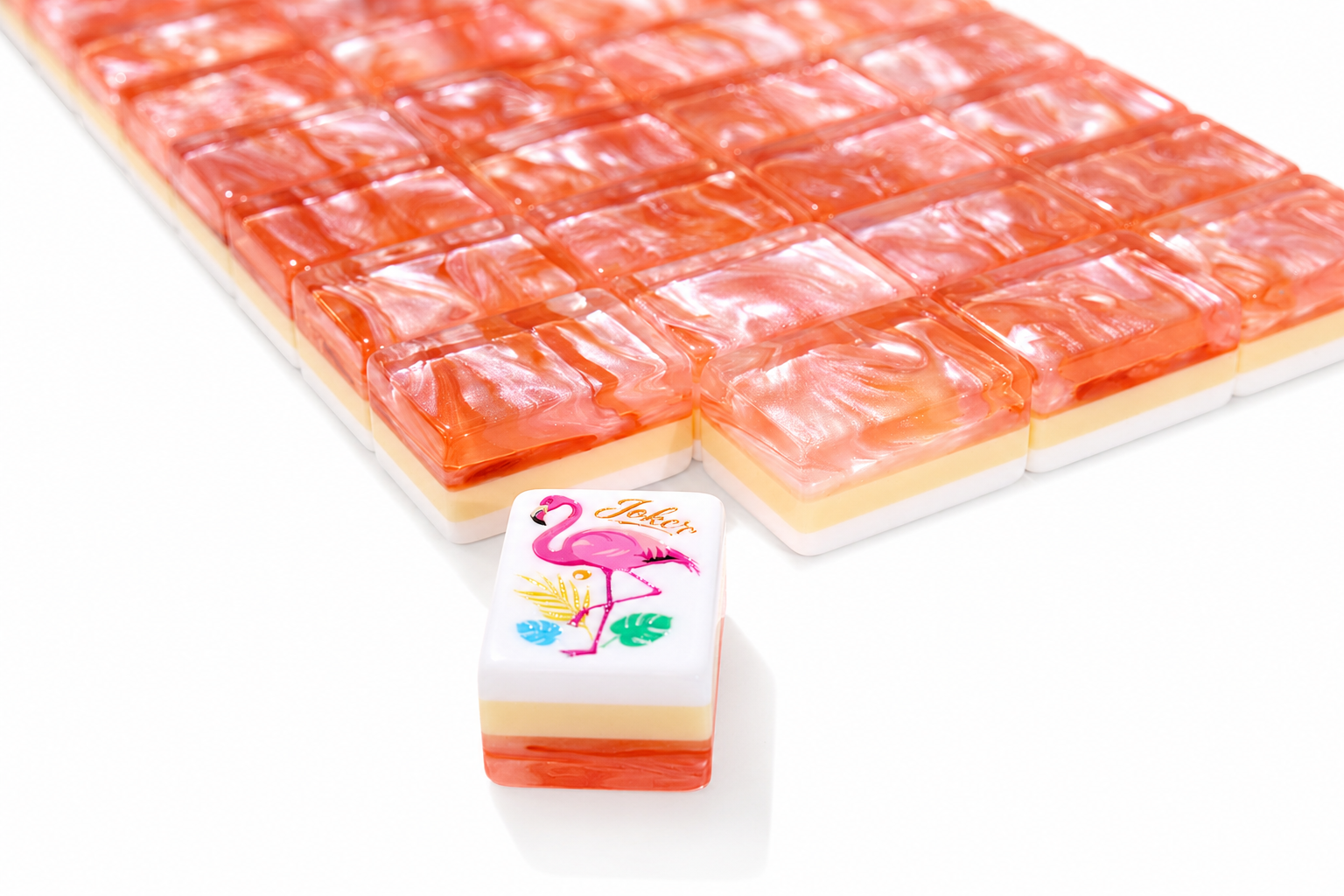 Close-up of coral-orange mahjong tiles with white faces and printed flamingo design