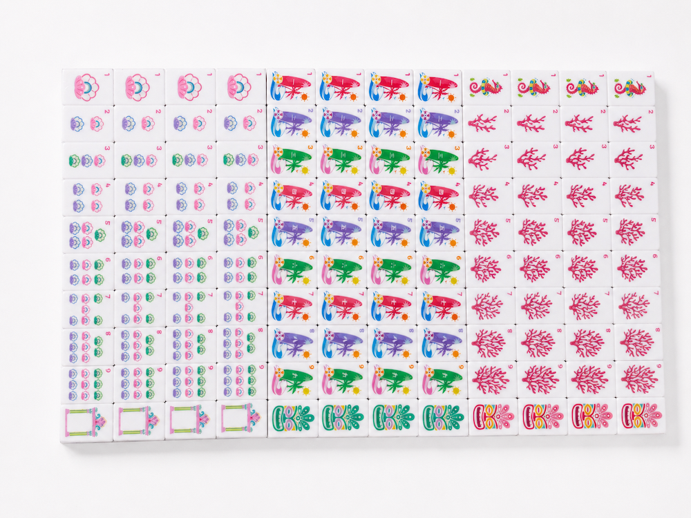 Mahjong tile set with pink, blue, green and red illustrated tile faces on tray