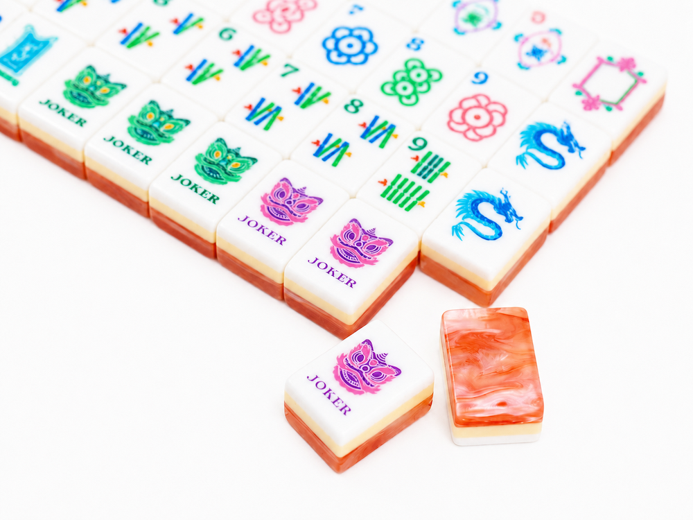 Close-up of coral mahjong tiles showing blue, green, and pink symbol tiles on white squares