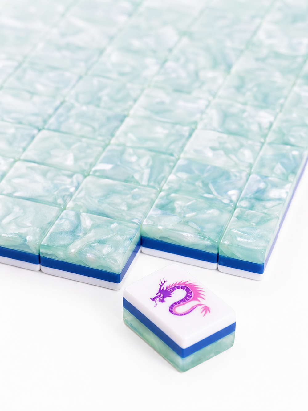 Stack of light blue translucent Mahjong tiles with a purple dragon joker tile in front