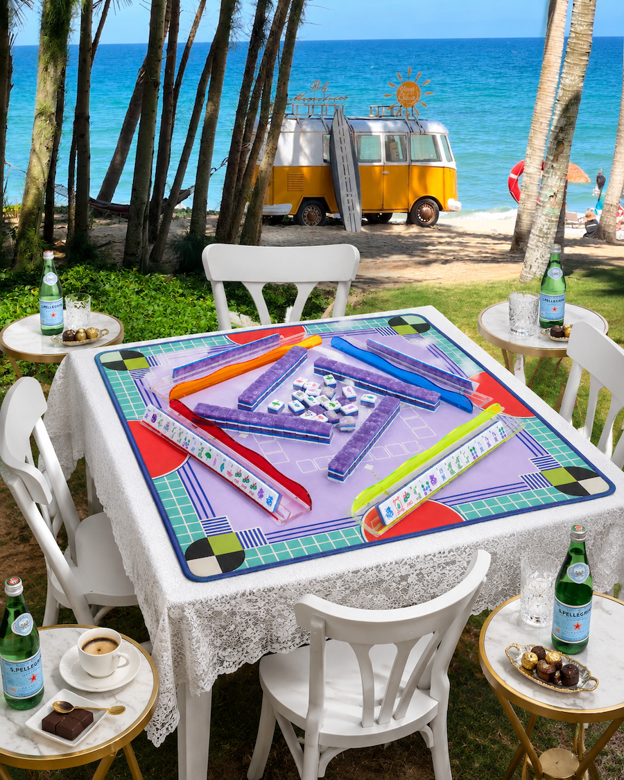 Outdoor mahjong tile table game with colorful play mat, tiles, and racks on table