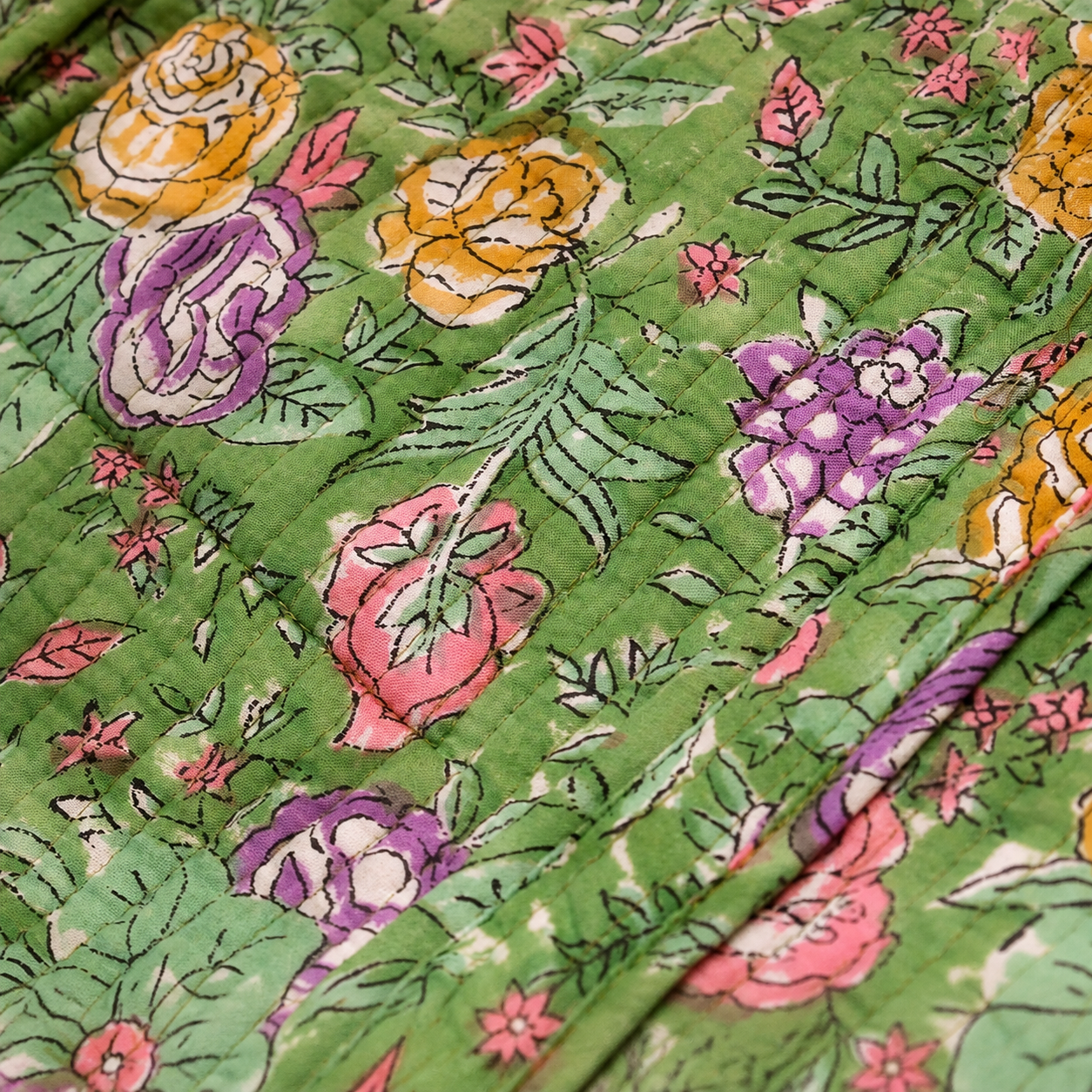 Quilted green cotton tote with colorful floral applique and dense stitched texture