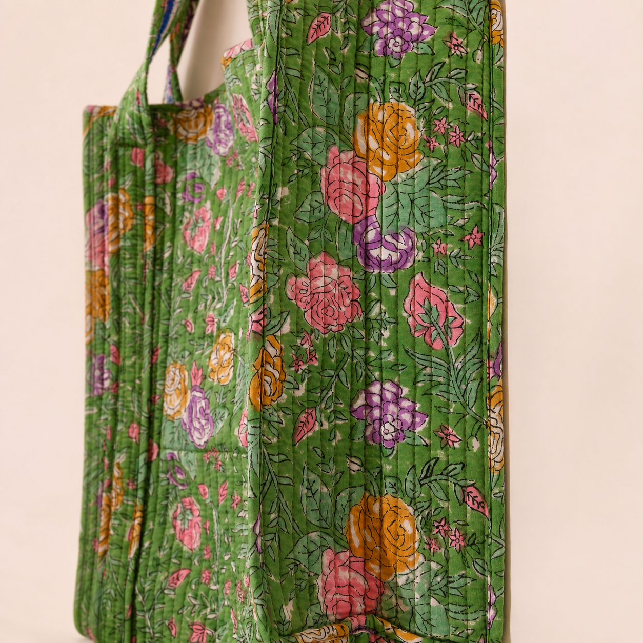 Floral quilted tote bag with green handles and vertical stitched panel details