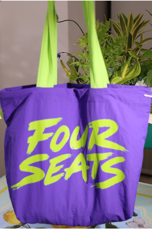 Purple tote bag with neon lime “Four Seats” graphic and lime carry handles