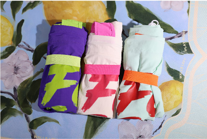 Foldable tote bags in purple, pink, and mint with “Four Seats” prints and straps