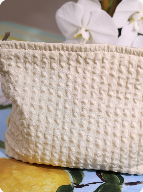 Textured ivory fabric pouch with gathered top and subtle raised pattern