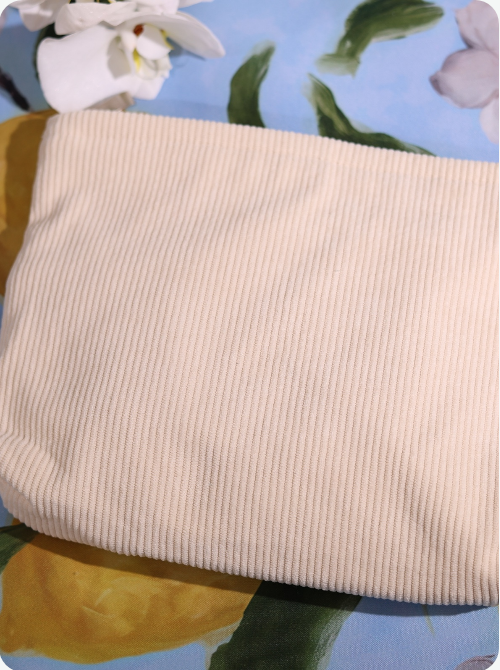 Ribbed light ivory fabric pouch with smooth top edge and rounded sides