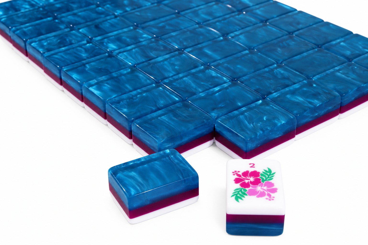 Close-up of blue glossy mahjong tiles with floral designs on the tile edges